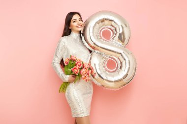 Güzel genç bir kadın elinde bir buket lale çiçeği ve 8 numaralı balon ile bahar tatilini kutluyor. 8 Mart Kadınlar Günü