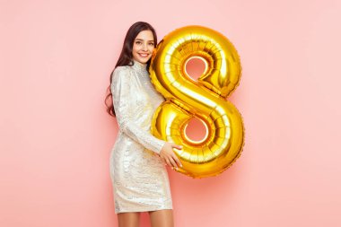 8 numaralı balonu tutan şenlikli elbisesiyle genç ve güzel bir kadın bahar tatilini kutluyor. 8 Mart Kadınlar Günü