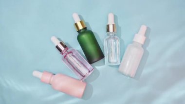 Kozmetik spa tıbbi cilt bakımı, mavi arka planda kolajen içeren cam serum şişesi. Yaşlanma önleyici bakım, nemlendirici ve temizlik için tıbbi ürün reklamı.