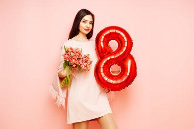 Güzel genç bir kadın elinde bir buket lale çiçeği ve 8 numaralı balon ile bahar tatilini kutluyor. 8 Mart Kadınlar Günü