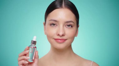 Elinde kozmetik yağ serumu ya da hyaluronik asit dolu bir kavanoz tutan güzel genç kadın. Mükemmel bir yüz derisi. Kozmetik cilt bakımı. Yavaş çekim