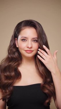 Güzel model kadınların dalgaları ve parlak saçları vardır. Kıvırcık saçlı, küpeli ve mücevherli esmer kız. Yavaş çekim videosu