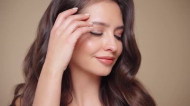 Güzel model kadınların dalgaları ve parlak saçları vardır. Kıvırcık saçlı, küpeli ve mücevherli esmer kız. Yavaş çekim videosu