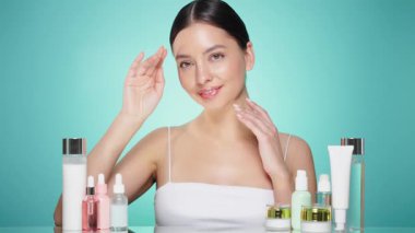 Doğal malzemelere dayalı kozmetik ürünler, fırça, tonik, vücut bakımı. Doğal kozmetik ürünleri. Açık mavi arka planda, kozmetik işlemleri için kavanozlar, şişeler ve tüplerin arasında genç bir kadın.