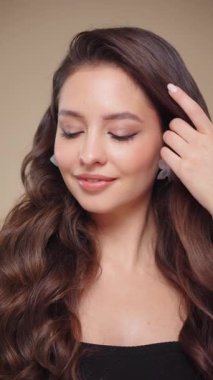 Güzel model kadınların dalgaları ve parlak saçları vardır. Kıvırcık saçlı, küpeli ve mücevherli esmer kız. Yavaş çekim videosu