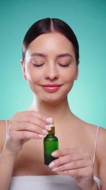 Elinde kozmetik yağ serumu ya da hyaluronik asit dolu bir kavanoz tutan güzel genç kadın. Mükemmel bir yüz derisi. Kozmetik cilt bakımı. Yavaş çekim, dikey video