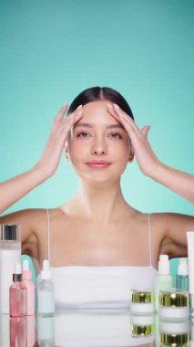 Doğal malzemelere dayalı kozmetik ürünler, fırça, tonik, vücut bakımı. Doğal kozmetik ürünleri. Açık mavi arka planda, kozmetik işlemleri için kavanozlar, şişeler ve tüplerin arasında genç bir kadın.