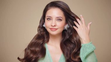 Güzel model kadınların dalgaları ve parlak saçları vardır. Kıvırcık saçlı, küpeli ve mücevherli esmer kız. Yavaş çekim videosu