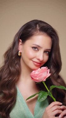 Güzel model kadınların dalgaları ve parlak saçları vardır. Kıvırcık saçlı, küpeli ve mücevherli esmer kız. Gül çiçekli kadın. Yavaş çekim videosu