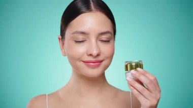 Güzellik kraliçesi yüzüne krem sürüyor. Temiz tenli genç bir kadın. Yüz kremi kavanozu olan bir model.