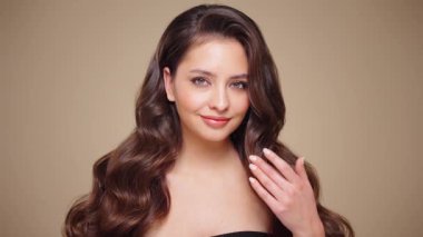 Güzel model kadınların dalgaları ve parlak saçları vardır. Kıvırcık saçlı, küpeli ve mücevherli esmer kız. Yavaş çekim videosu
