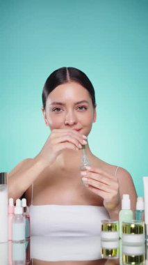 Doğal malzemelere dayalı kozmetik ürünler, fırça, tonik, vücut bakımı. Doğal kozmetik ürünleri. Açık mavi arka planda, kozmetik işlemleri için kavanozlar, şişeler ve tüplerin arasında genç bir kadın.