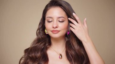 Güzel model kadınların dalgaları ve parlak saçları vardır. Kıvırcık saçlı, küpeli ve mücevherli esmer kız. Yavaş çekim videosu