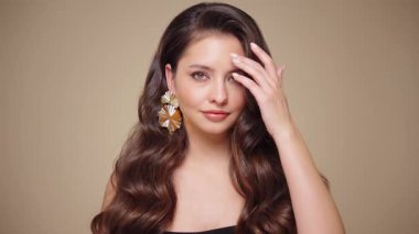 Güzel model kadınların dalgaları ve parlak saçları vardır. Kıvırcık saçlı, küpeli ve mücevherli esmer kız. Yavaş çekim videosu