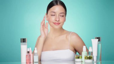 Doğal malzemelere dayalı kozmetik ürünler, fırça, tonik, vücut bakımı. Doğal kozmetik ürünleri. Açık mavi arka planda, kozmetik işlemleri için kavanozlar, şişeler ve tüplerin arasında genç bir kadın.