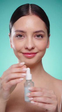 Elinde kozmetik yağ serumu ya da hyaluronik asit dolu bir kavanoz tutan güzel genç kadın. Mükemmel bir yüz derisi. Kozmetik cilt bakımı. Yavaş çekim, dikey video