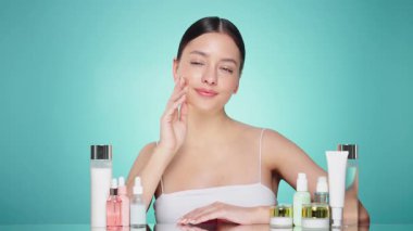Doğal malzemelere dayalı kozmetik ürünler, fırça, tonik, vücut bakımı. Doğal kozmetik ürünleri. Açık mavi arka planda, kozmetik işlemleri için kavanozlar, şişeler ve tüplerin arasında genç bir kadın.