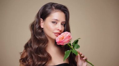 Güzel model kadınların dalgaları ve parlak saçları vardır. Kıvırcık saçlı, küpeli ve mücevherli esmer kız. Gül çiçekli kadın. Yavaş çekim videosu