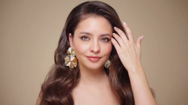 Güzel model kadınların dalgaları ve parlak saçları vardır. Kıvırcık saçlı, küpeli ve mücevherli esmer kız. Yavaş çekim videosu