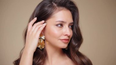 Güzel model kadınların dalgaları ve parlak saçları vardır. Kıvırcık saçlı, küpeli ve mücevherli esmer kız. Yavaş çekim videosu