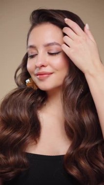 Güzel model kadınların dalgaları ve parlak saçları vardır. Kıvırcık saçlı, küpeli ve mücevherli esmer kız. Yavaş çekim videosu