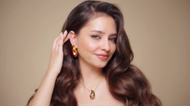 Güzel model kadınların dalgaları ve parlak saçları vardır. Kıvırcık saçlı, küpeli ve mücevherli esmer kız. Yavaş çekim videosu