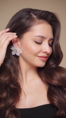 Güzel model kadınların dalgaları ve parlak saçları vardır. Kıvırcık saçlı, küpeli ve mücevherli esmer kız. Yavaş çekim videosu