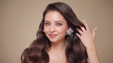 Güzel model kadınların dalgaları ve parlak saçları vardır. Kıvırcık saçlı, küpeli ve mücevherli esmer kız. Yavaş çekim videosu