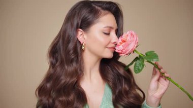 Güzel model kadınların dalgaları ve parlak saçları vardır. Kıvırcık saçlı, küpeli ve mücevherli esmer kız. Gül çiçekli kadın. Yavaş çekim videosu