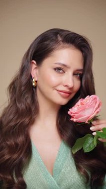 Güzel model kadınların dalgaları ve parlak saçları vardır. Kıvırcık saçlı, küpeli ve mücevherli esmer kız. Gül çiçekli kadın. Yavaş çekim videosu