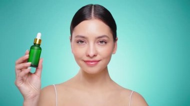 Elinde kozmetik yağ serumu ya da hyaluronik asit dolu bir kavanoz tutan güzel genç kadın. Mükemmel bir yüz derisi. Kozmetik cilt bakımı. Yavaş çekim