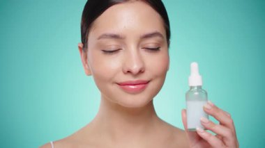 Elinde kozmetik yağ serumu ya da hyaluronik asit dolu bir kavanoz tutan güzel genç kadın. Mükemmel bir yüz derisi. Kozmetik cilt bakımı. Yavaş çekim