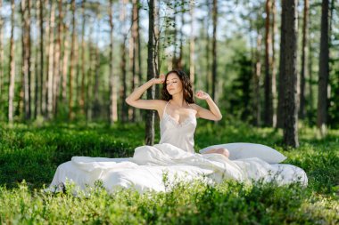 Yaz ormanında bir kadın yatakta uyur. Kız bir yaz ormanında uyanıyor.