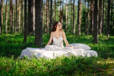 Yaz ormanında bir kadın yatakta uyur. Kız yaz ormanında uyanıyor. Eko-konfor ve rahatlama