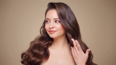 Güzel model kadınların dalgaları ve parlak saçları vardır. Kıvırcık saçlı, küpeli ve mücevherli esmer kız. Yavaş çekim videosu