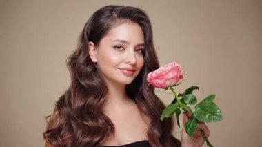 Güzel model kadınların dalgaları ve parlak saçları vardır. Kıvırcık saçlı, küpeli ve mücevherli esmer kız. Gül çiçekli kadın. Yavaş çekim videosu