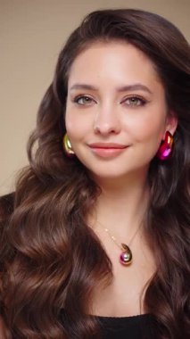 Güzel model kadınların dalgaları ve parlak saçları vardır. Kıvırcık saçlı, küpeli ve mücevherli esmer kız. Yavaş çekim videosu