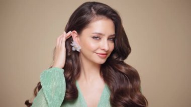 Güzel model kadınların dalgaları ve parlak saçları vardır. Kıvırcık saçlı, küpeli ve mücevherli esmer kız. Yavaş çekim videosu