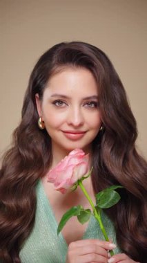 Güzel model kadınların dalgaları ve parlak saçları vardır. Kıvırcık saçlı, küpeli ve mücevherli esmer kız. Gül çiçekli kadın. Yavaş çekim videosu