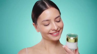 Güzellik kraliçesi yüzüne krem sürüyor. Temiz tenli genç bir kadın. Yüz kremi kavanozu olan bir model.