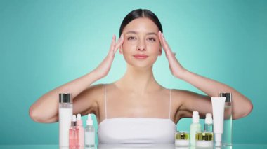 Doğal malzemelere dayalı kozmetik ürünler, fırça, tonik, vücut bakımı. Doğal kozmetik ürünleri. Açık mavi arka planda, kozmetik işlemleri için kavanozlar, şişeler ve tüplerin arasında genç bir kadın.
