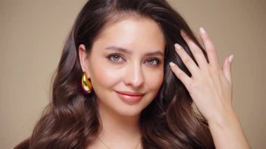 Güzel model kadınların dalgaları ve parlak saçları vardır. Kıvırcık saçlı, küpeli ve mücevherli esmer kız. Yavaş çekim videosu