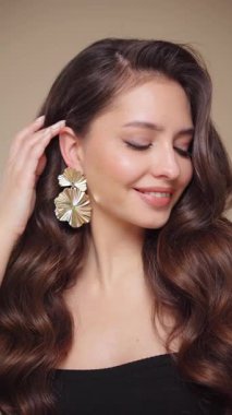 Güzel model kadınların dalgaları ve parlak saçları vardır. Kıvırcık saçlı, küpeli ve mücevherli esmer kız. Yavaş çekim videosu