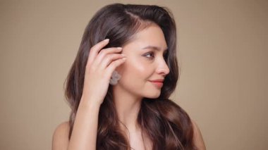 Güzel model kadınların dalgaları ve parlak saçları vardır. Kıvırcık saçlı, küpeli ve mücevherli esmer kız. Yavaş çekim videosu