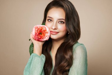 Parlak esmer saçlı güzel bir genç kadın. Gül çiçekli kız. Sağlıklı ciltli bir model. Kozmetik, güzellik ve kaplıca