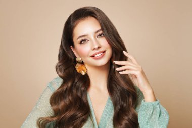 Mükemmel makyajlı esmer kız. Uzun kıvırcık saçlı, gülümseyen güzel model kadın. Bakım ve güzellik saç ürünleri