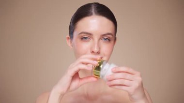 Güzellik kraliçesi yüzüne krem sürüyor. Temiz tenli genç bir kadın. Yüz kremi kavanozu olan bir model.