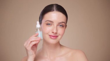 Güzel Genç Kadın Kusursuz Yüzüne Dokunuyor. Doğal Kozmetik Teni Ürünleri. Kadın nemlendirici yüz bakımı gösteriyor. İzole edilmiş arkaplanı olan yakın plan portresi yükseliyor. Yavaş çekim