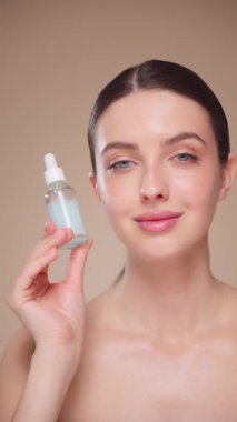 Elinde kozmetik yağ serumu ya da hyaluronik asit dolu bir kavanoz tutan güzel genç kadın. Mükemmel bir yüz derisi. Kozmetik cilt bakımı. Yavaş çekim, dikey video