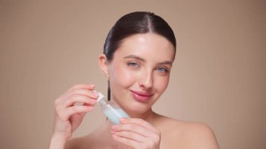 Güzel Genç Kadın Kusursuz Yüzüne Dokunuyor. Doğal Kozmetik Teni Ürünleri. Kadın nemlendirici yüz bakımı gösteriyor. İzole edilmiş arkaplanı olan yakın plan portresi yükseliyor. Yavaş çekim